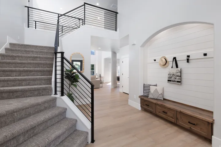 Open foyer with light wood-finish flooring, a built-in wooden bench with three drawers, and a shiplap accent wall