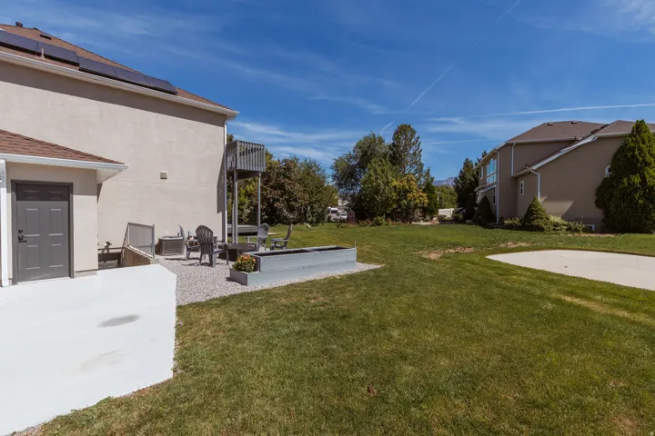 Expansive green lawn with a concrete patio and gravel seating area