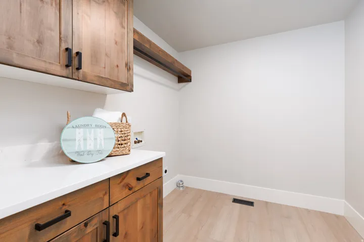 Wood-finish flooring, white walls, and wood cabinetry with black hardware
