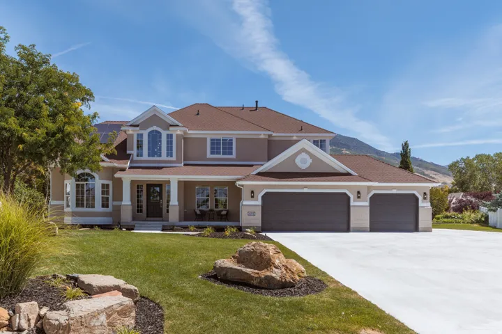 Stucco exterior with a columned porch, multiple arched windows, and a multi-car garage