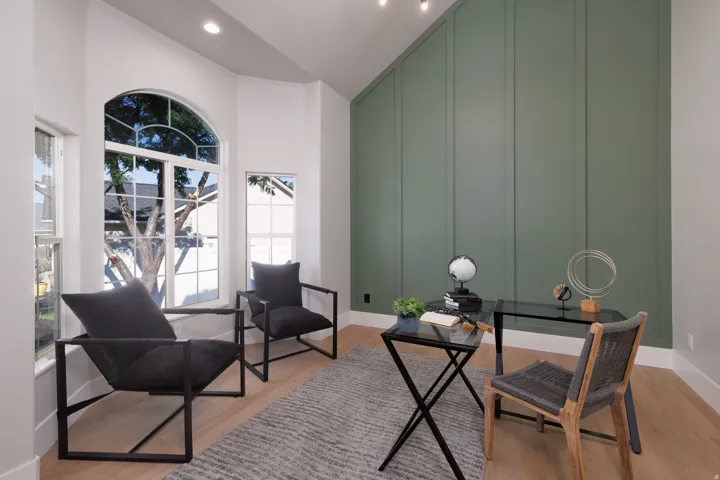 Arched window, wood-finish flooring, accent wall with vertical paneling, recessed lighting, vaulted ceiling