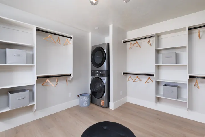 Integrated laundry appliances, built-in shelving, hanging rods, light wood-finish flooring, and recessed ceiling lighting