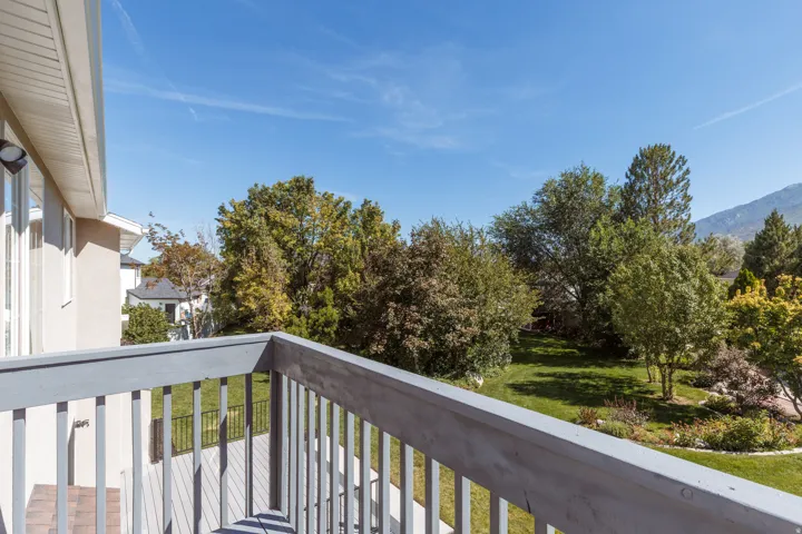 Upper-level balcony with wood railing, offering expansive green space and mature tree canopy