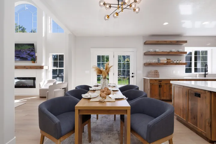 Vaulted ceilings with architectural windows, modern linear chandelier, wood-finish flooring, built-in fireplace, and custom wood cabinetry with open shelving
