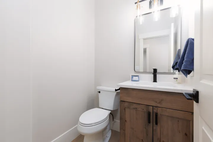 Wood-finish vanity with white countertop, undermount sink, and matte black faucet