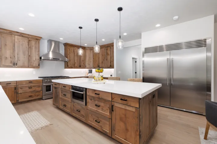Kitchen featuring a large central island, wood-finish cabinetry, stainless steel appliances, pendant lighting, and recessed ceiling lights