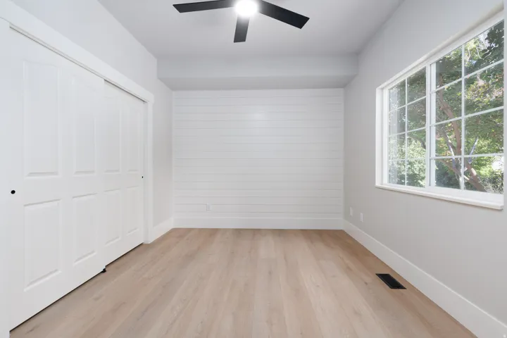 Room featuring wood-finish flooring, a contemporary ceiling fan, and a large window with multiple panes
