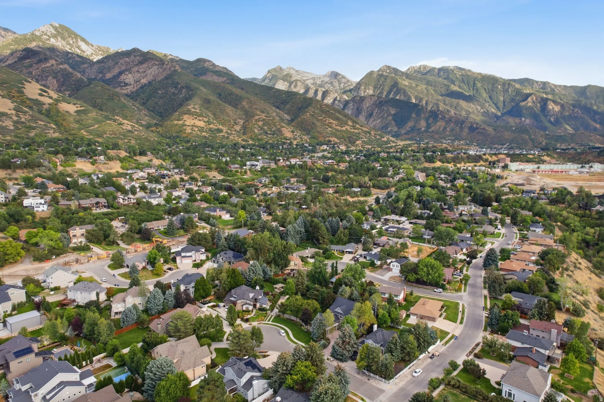 Mountainous terrain backdrop, residential community, mature trees, paved streets, varied architectural styles