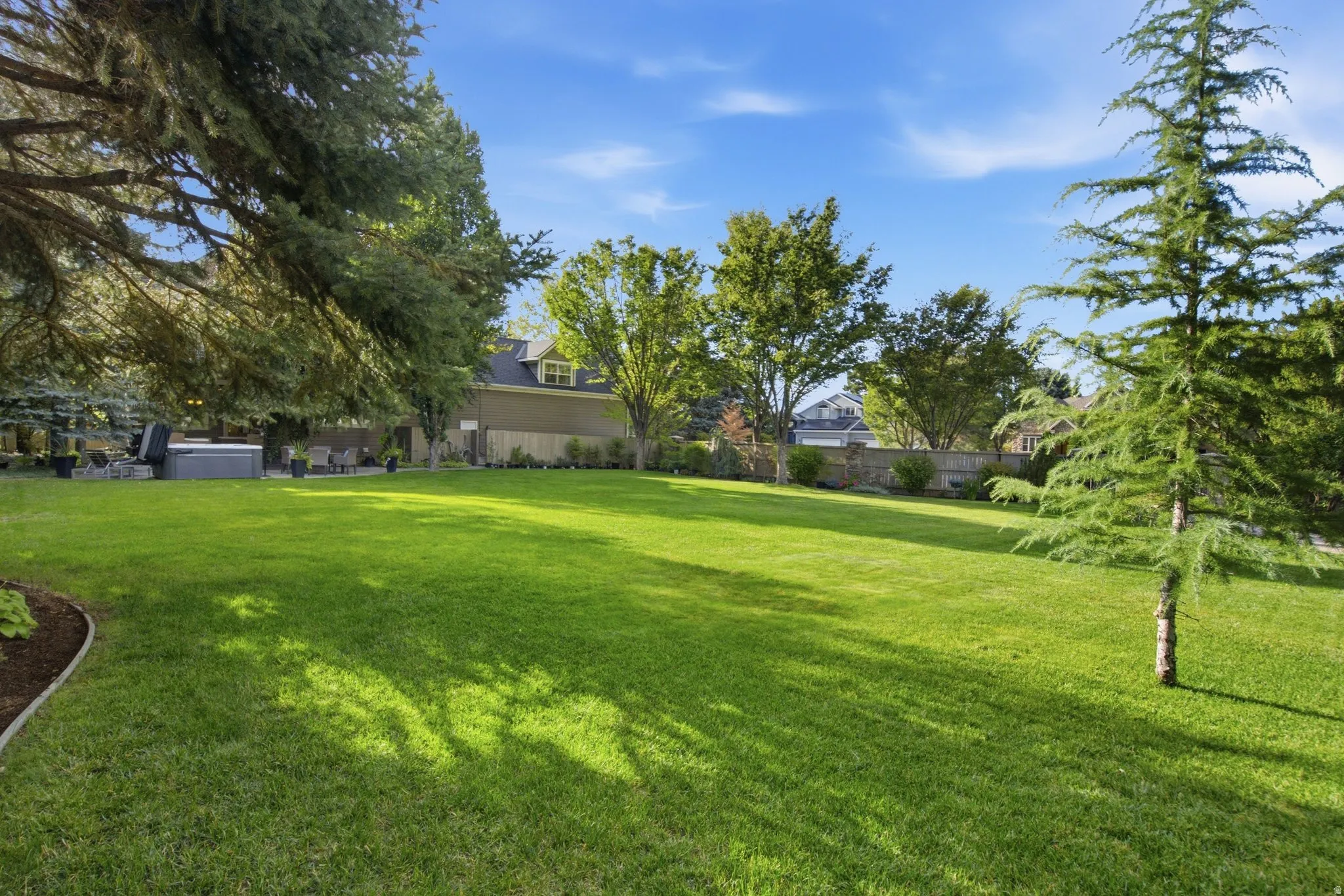 Expansive green lawn with mature trees and a dedicated patio area