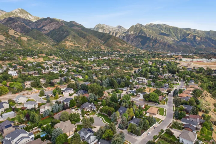 Mountainous terrain backdrop, residential community, mature trees, paved streets, varied architectural styles