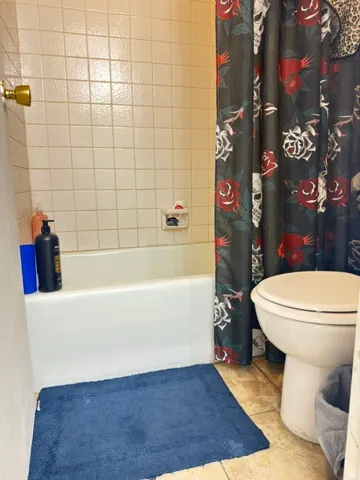 Bathtub with white tile surround and a wall-mounted shower fixture