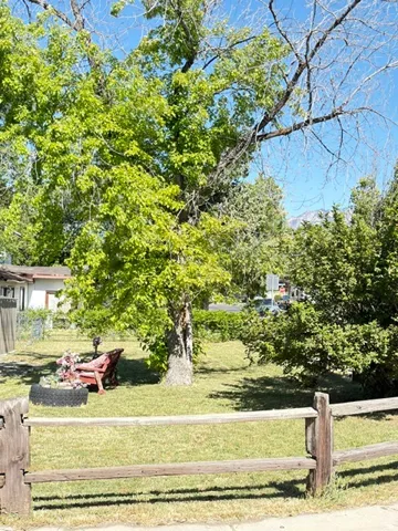 Expansive green lawn with mature trees and a rustic wood-rail fence