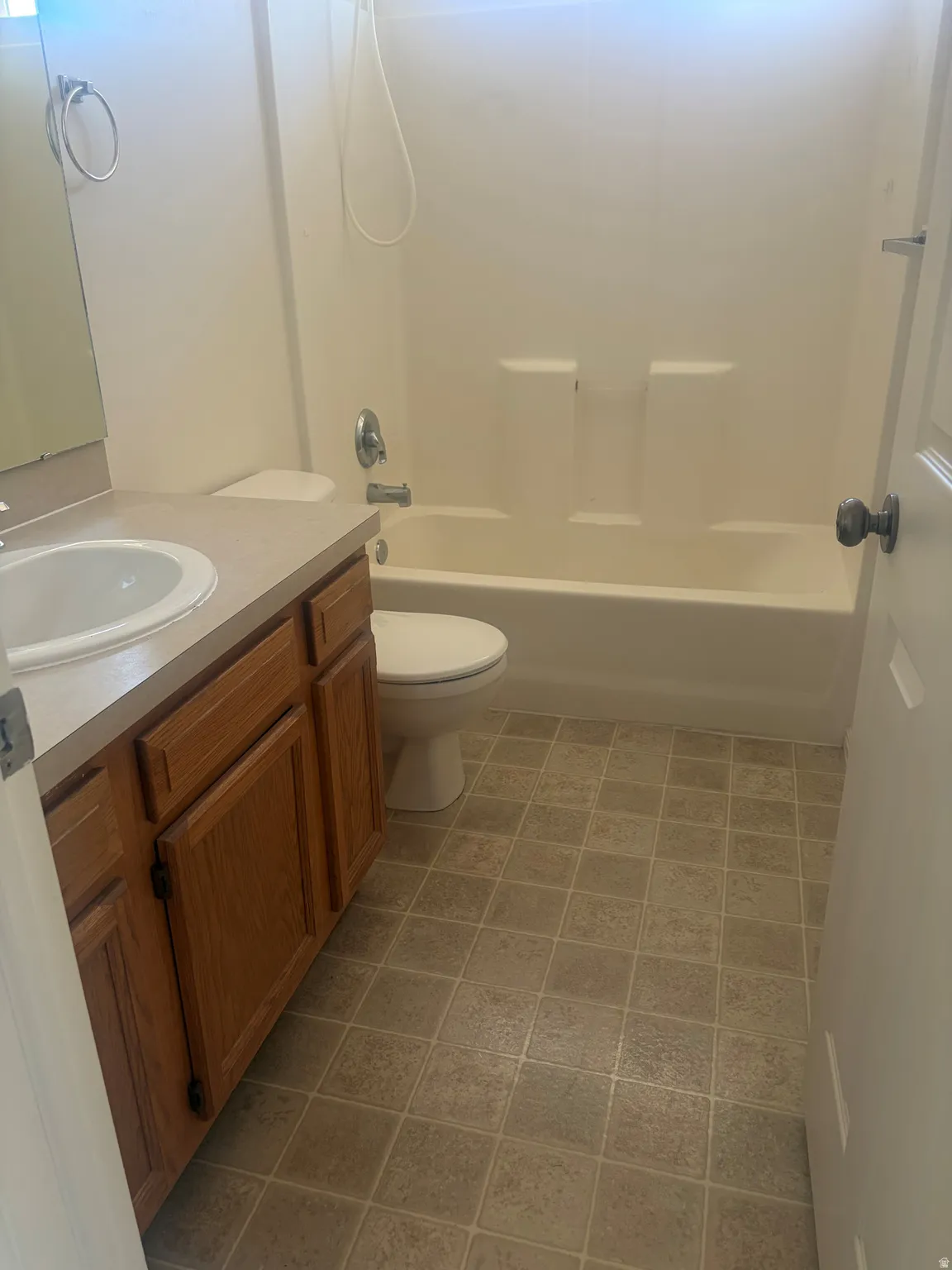Bathroom featuring a built-in vanity with wood-finish cabinetry, a white drop-in sink, and a combination tub/shower