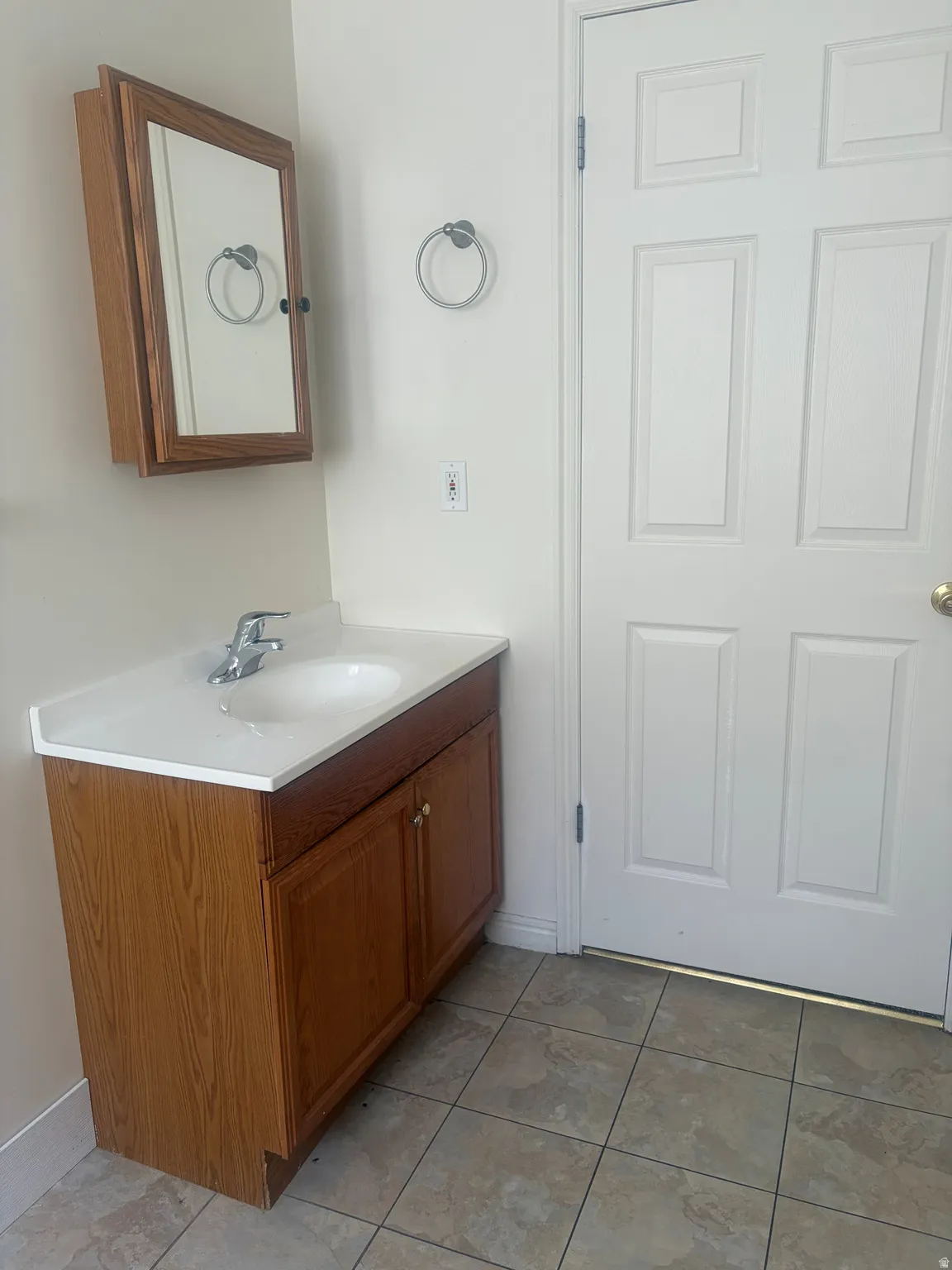 Wood-finish vanity with white countertop, integrated sink, and chrome faucet