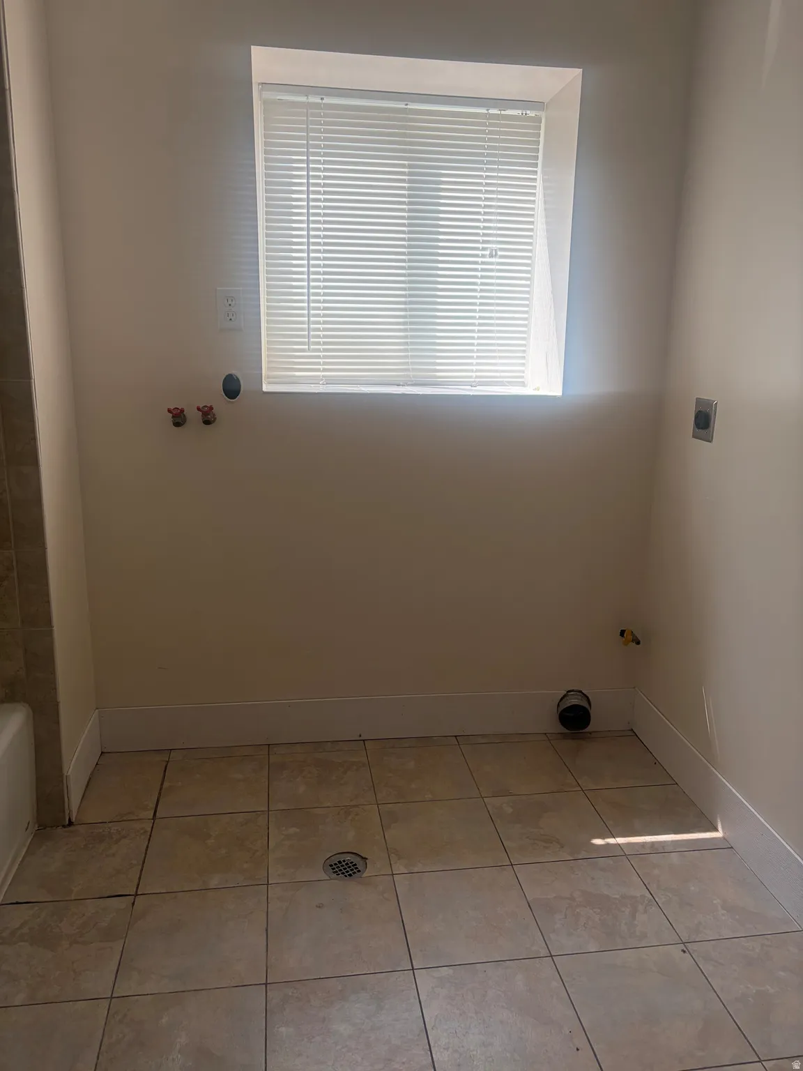 Laundry area featuring tile flooring, window with blinds, and utility hookups