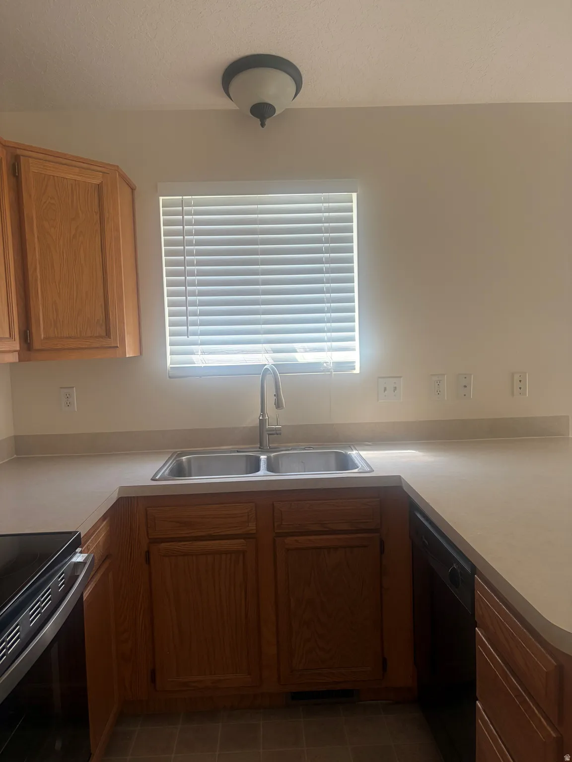 Wood-finish cabinetry with a double basin stainless steel sink, a stainless steel faucet, and laminate countertops