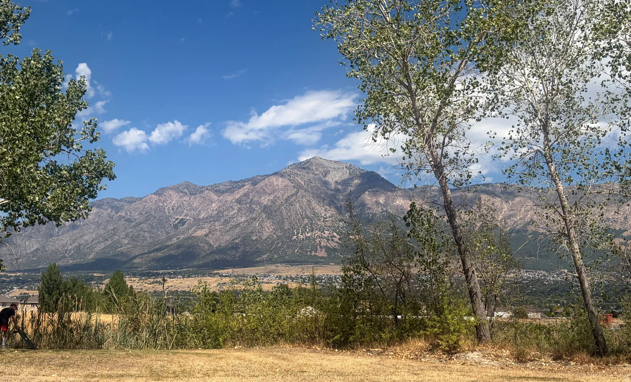 Expansive mountain range backdrop with distant residential structures
