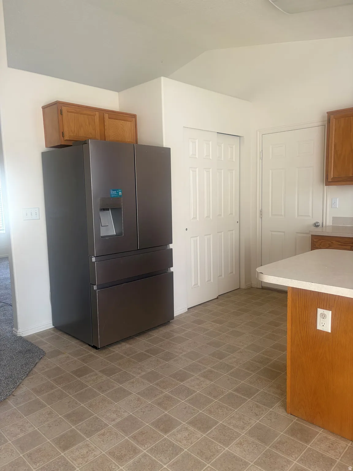 Kitchen area featuring wood-finish cabinetry, tile-pattern flooring, and a peninsula with countertop space