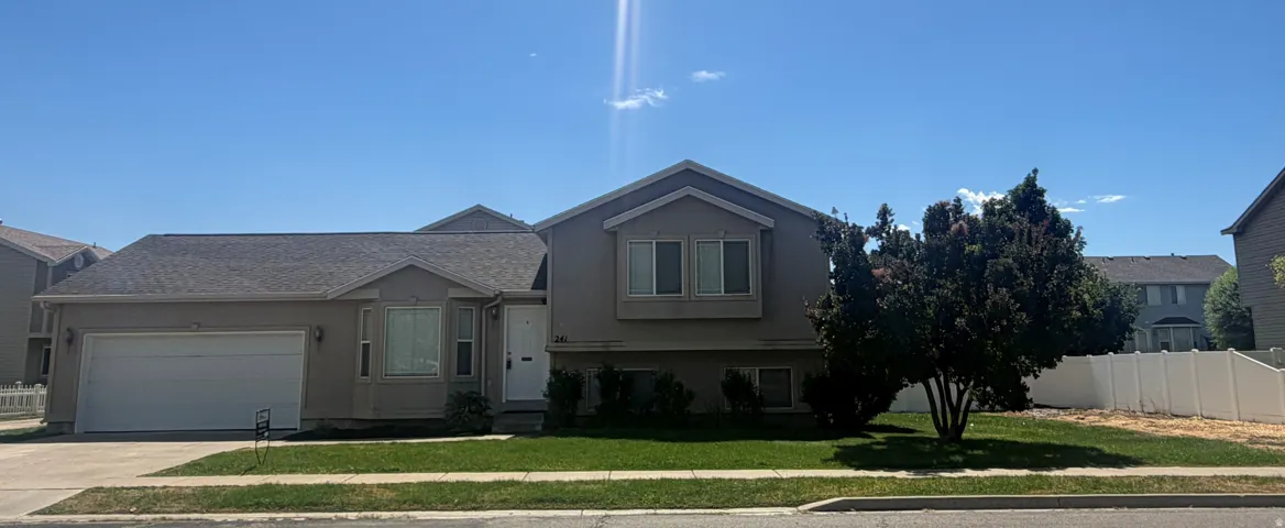 Stucco exterior with a pitched roof, attached two-car garage, and established front yard landscaping