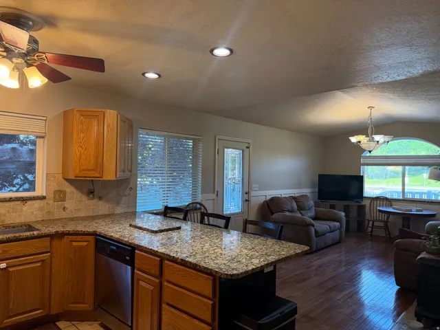 Kitchen featuring granite-finish countertops, wood cabinetry, and a tile backsplash