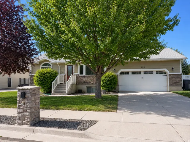 Stone-clad facade with neutral siding, arched window, and a white garage door featuring decorative hardware