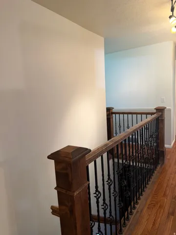 Hardwood flooring, dark wood newel posts, decorative wrought iron balusters, and a matching dark wood handrail