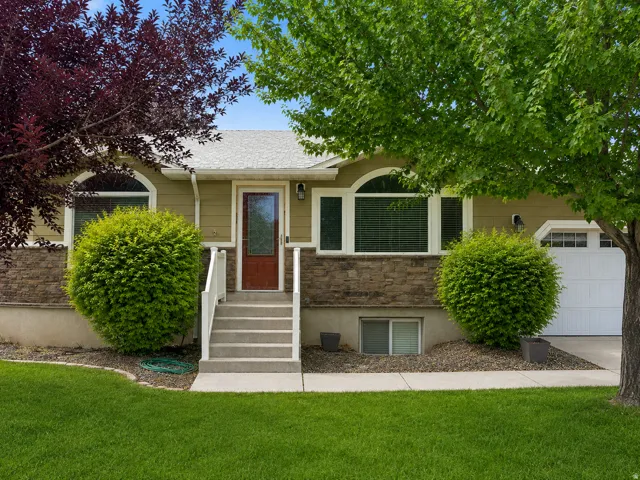 Exterior featuring stone veneer accents, concrete steps with white railings, a front entry door with glass panel, and arched transom windows