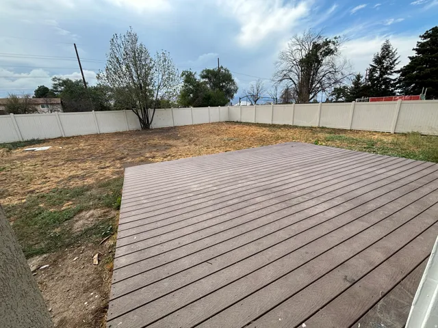 Expansive outdoor deck with composite decking, surrounded by a perimeter fence
