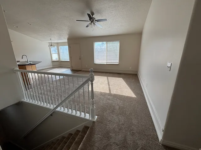 Carpeted living area with a ceiling fan, recessed lighting, and white window blinds