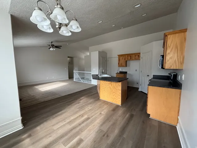 Kitchen featuring wood cabinetry, black countertops, and a stainless steel sink