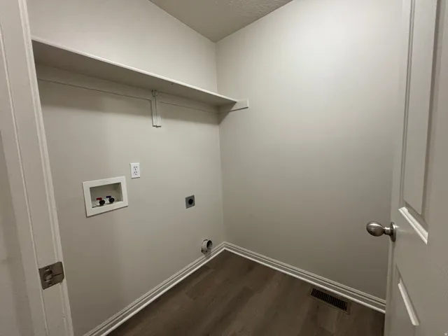 Dedicated laundry area featuring a built-in shelf, wood-finish flooring, and crisp white walls