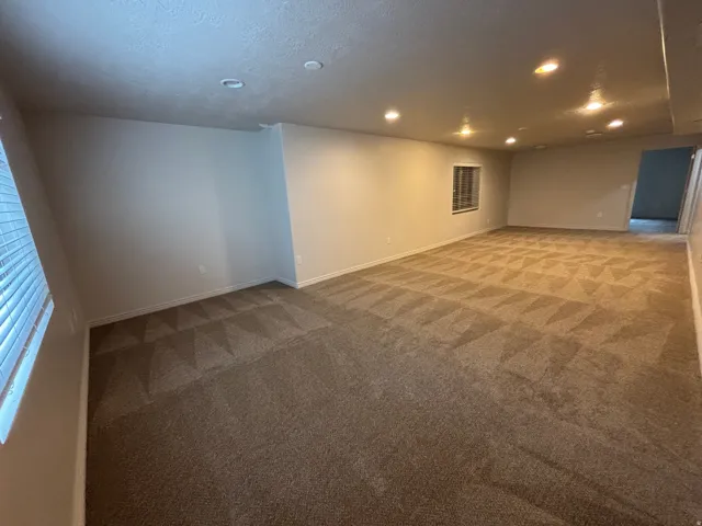 Expansive room featuring recessed lighting, a patterned carpet, painted walls, and a window with blinds