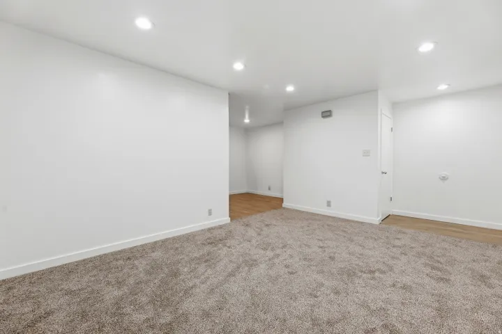 Recessed ceiling lighting, white painted walls, and carpet flooring