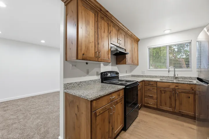Kitchen with wood-finish cabinetry, speckled countertops, and wood-finish flooring