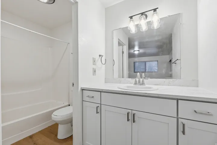 White vanity with brushed nickel hardware, integrated sink, and a countertop