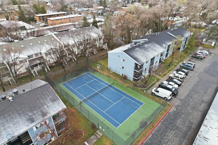 Community tennis court with blue playing surface, surrounded by fencing
