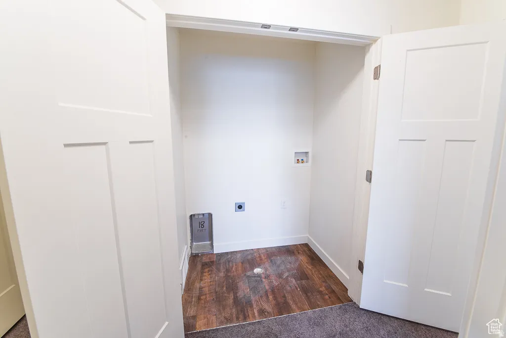Utility closet featuring wood-finish flooring, white paneled doors, and built-in laundry hookups