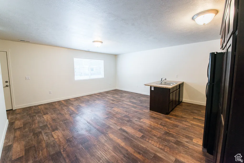 Wood-finish flooring throughout, bright white walls, compact kitchen island with a double basin sink and countertop, and built-in dark cabinetry