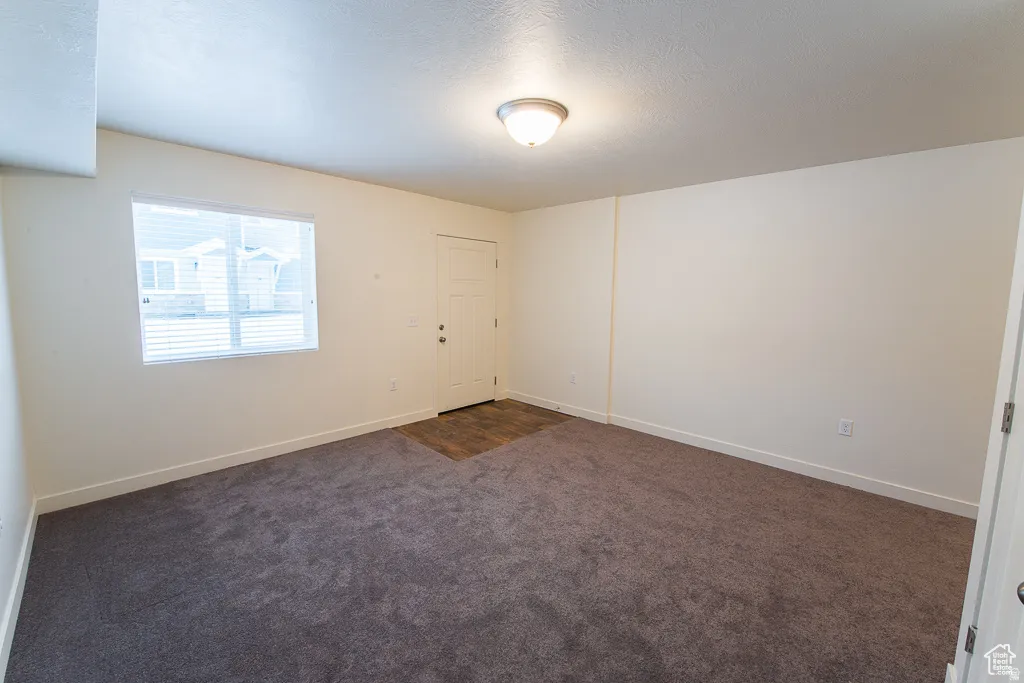 Neutral wall paint, textured ceiling, flush mount ceiling light, window with blinds, wood-finish flooring at entry