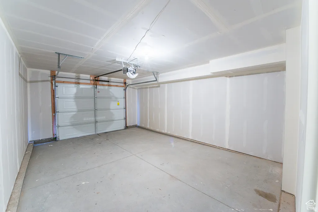 Single-bay garage with a sectional overhead door, automatic opener, and concrete flooring