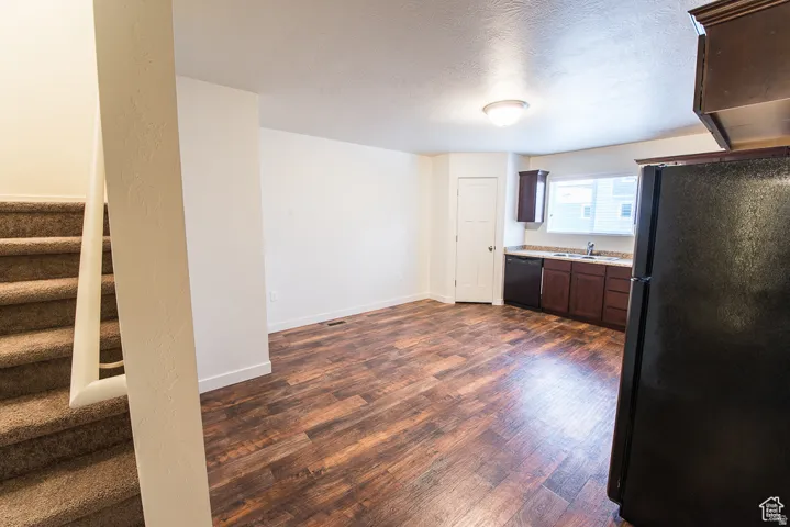 Kitchen with wood-finish flooring, dark wood-finish cabinetry, and a stainless steel sink