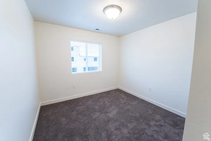 Neutral paint palette with a single window, white window blinds, and dark carpet flooring