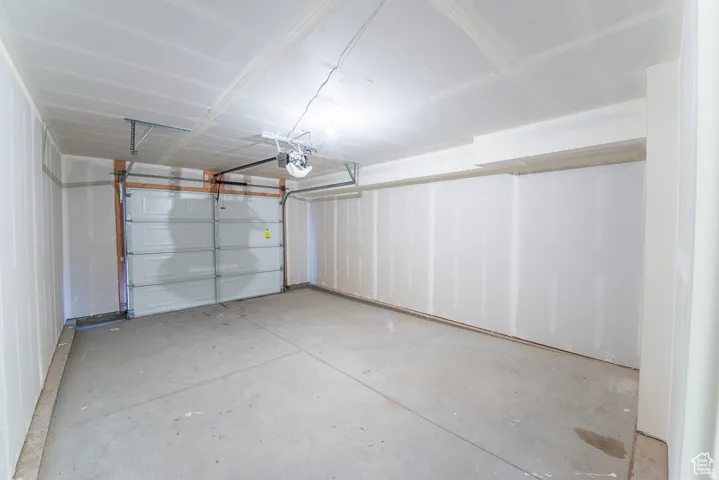 Single-bay garage with a sectional overhead door, automatic opener, and concrete flooring