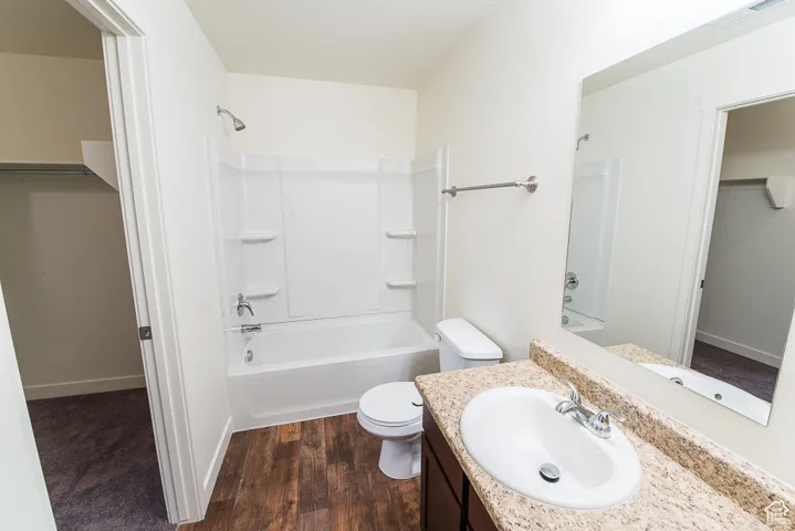 Wood-finish flooring, single vanity with a granite-style countertop, white oval sink, and chrome fixtures