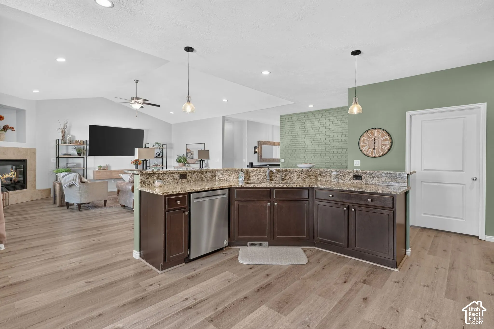 Spacious kitchen island with built-in stainless steel dishwasher, wood-finish flooring, recessed lighting, and vaulted ceiling