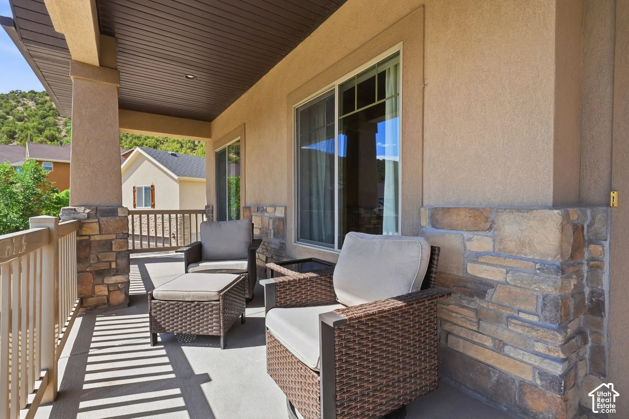 Covered patio featuring stone columns, wood-finish ceiling, stucco exterior, and sliding glass doors
