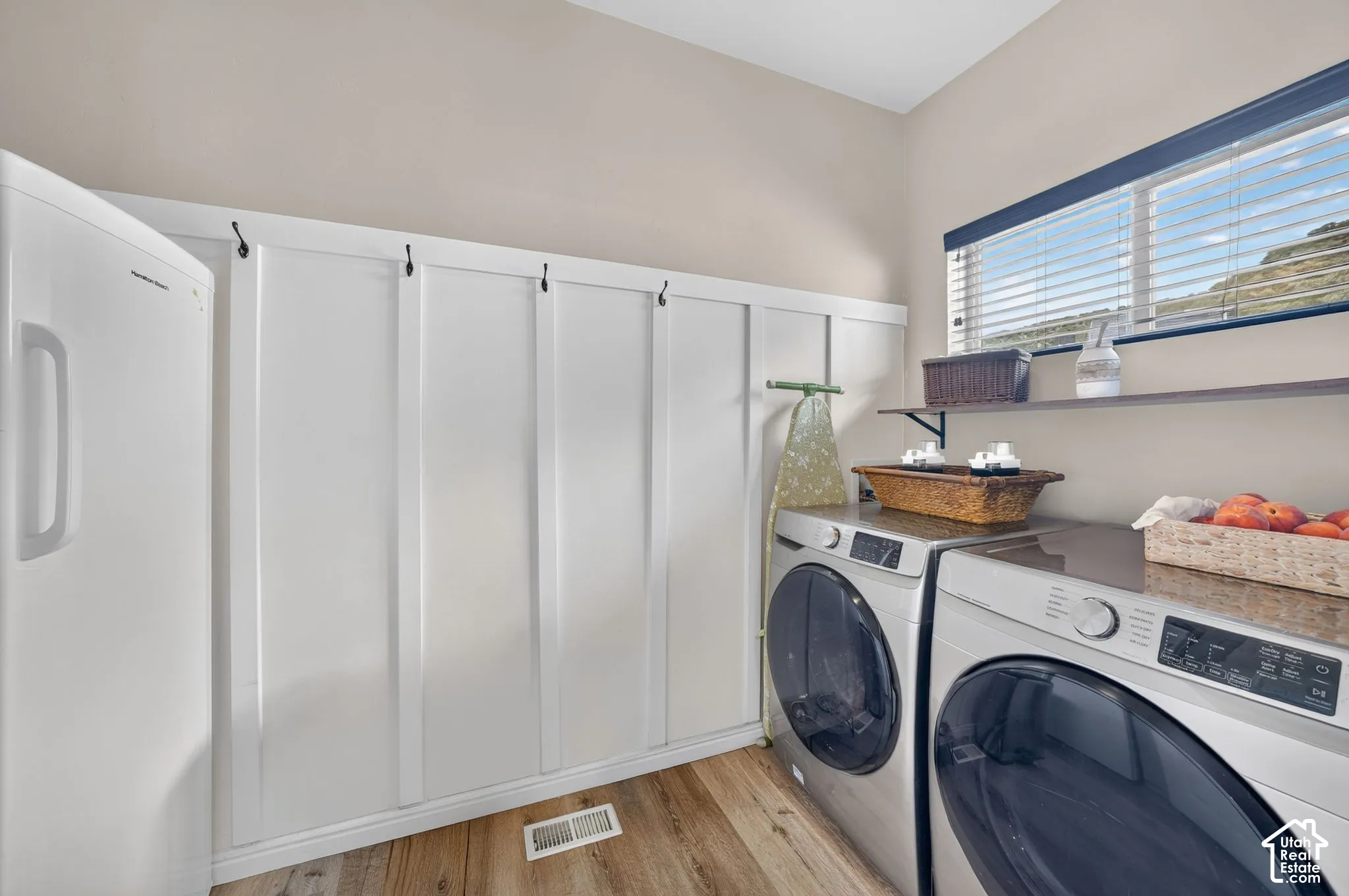 Wood-finish flooring, built-in board and batten paneling, window with blinds, and built-in shelving