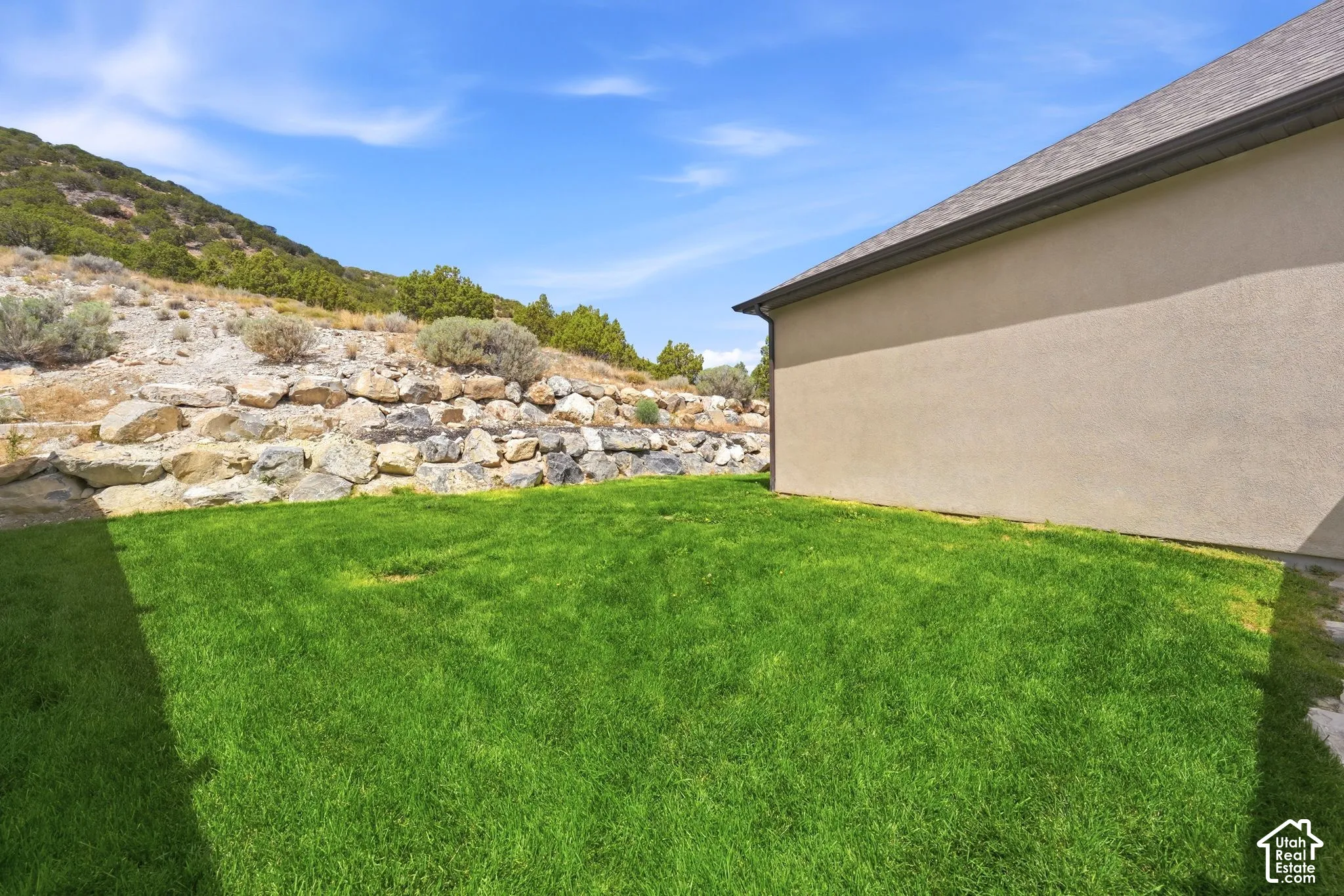 Expansive lawn area with a natural rock retaining wall
