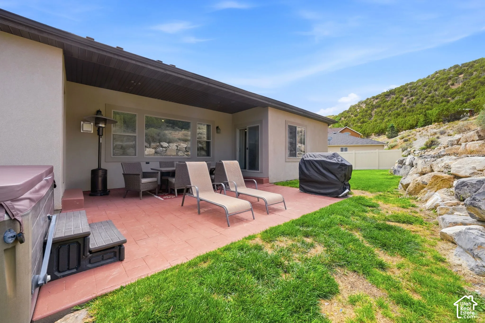 Expansive stamped concrete patio with an integrated hot tub and a covered dining area