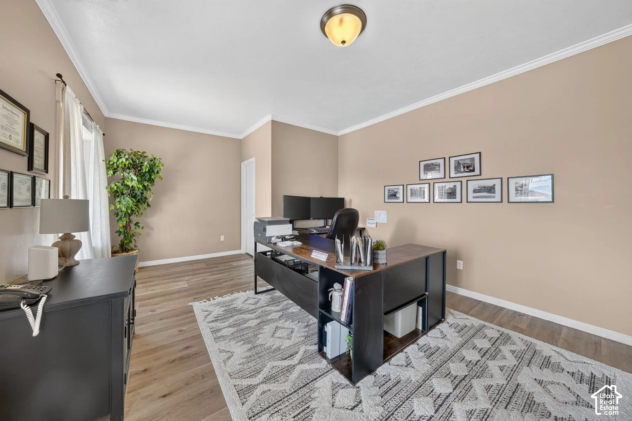 Recessed ceiling light fixture, crown molding, wood-finish flooring, and natural light from a window